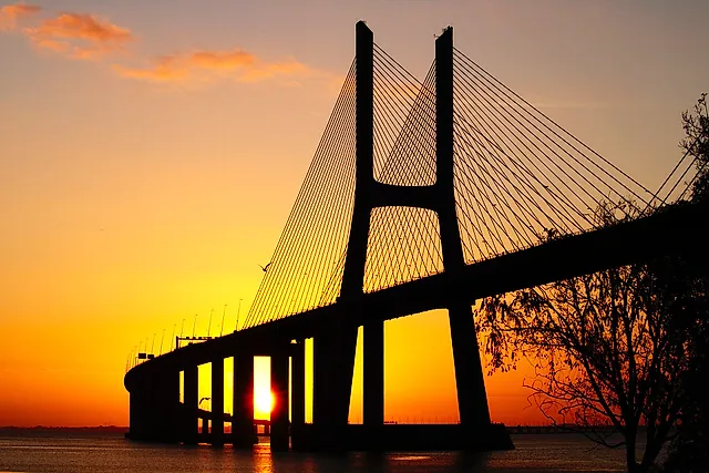 The pylon of the Vasco da Gama Bridge silhouetted against an orange sunrise